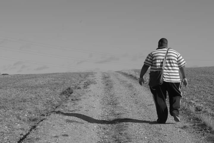 Man walking away along a dusty road