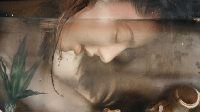 Lady immersing her face into water. Her face, with eyes closed, can e seen below the waterline.
